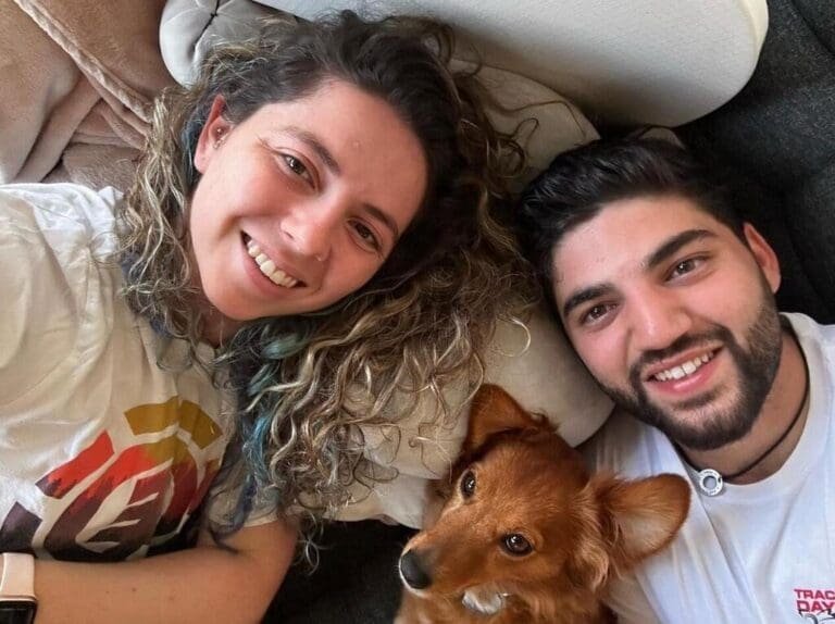 A smiling young couple with a small dog, sharing a happy moment together.