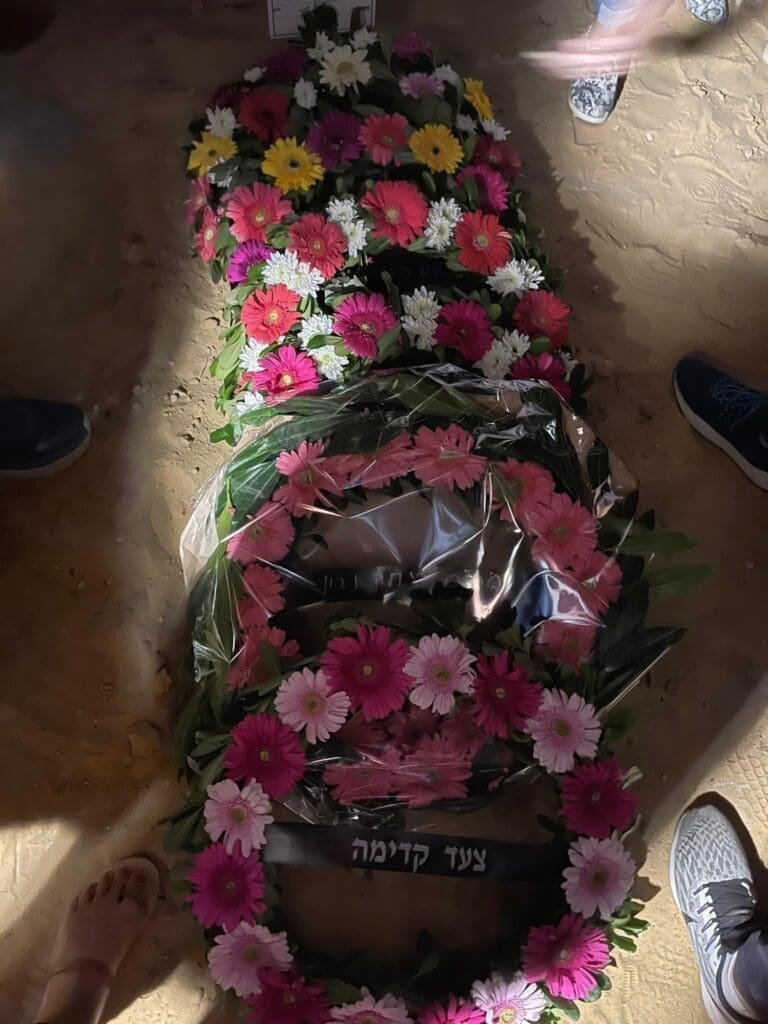 A gravesite adorned with flowers under the solemn shadow of night.