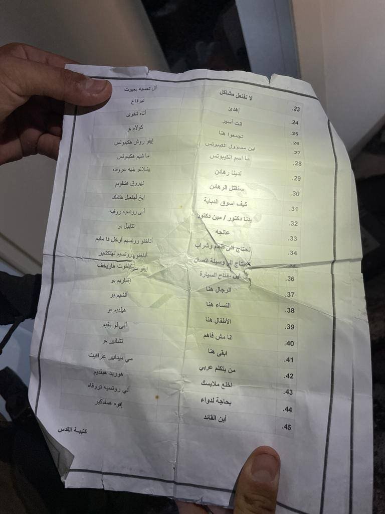 A hand holding a crumpled piece of paper with Arabic text and numbers.