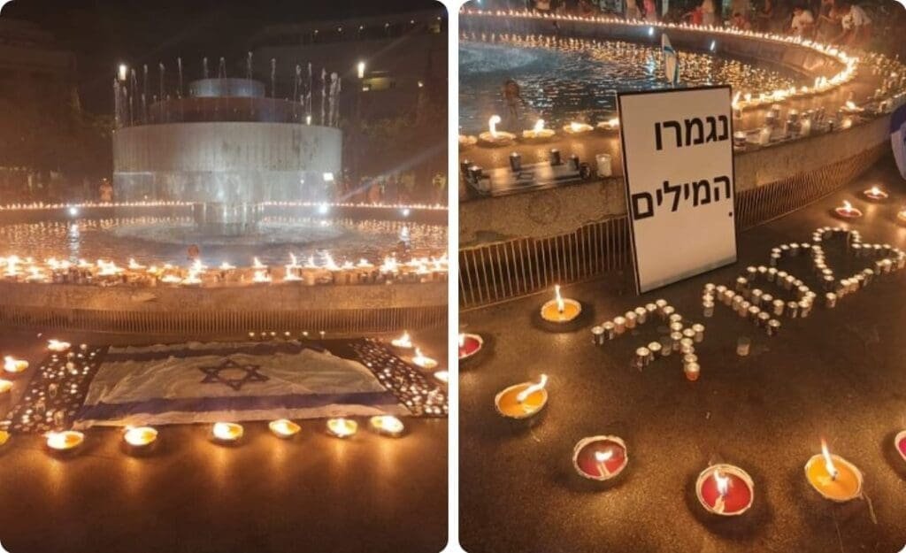 A poignant scene of candlelight vigil at Dizengoff Square in Tel Aviv, with candles arranged around an Israeli flag and a heart shape.