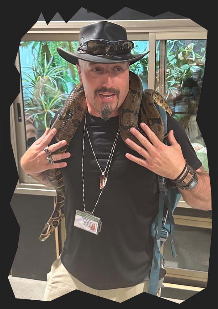 Shay Figenbaum at the Biblical Nature Museum in Beit Shemesh, Israel, playfully wearing a snake around his shoulders during a group tour.