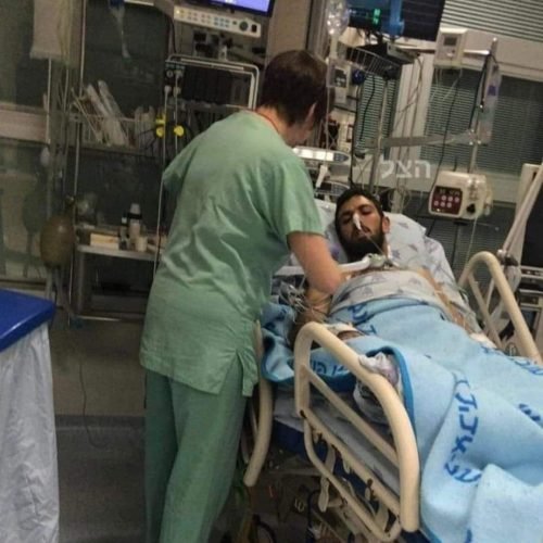 A healthcare professional attends to a patient in a hospital bed surrounded by medical equipment